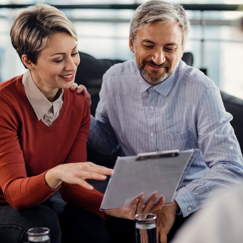 Happy couple analyzing documents while having a meeting with insurance agent in the office.